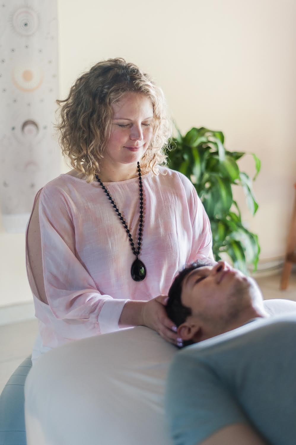 Petra, eyes closed, gently holding a client's head during a CranioSacral session